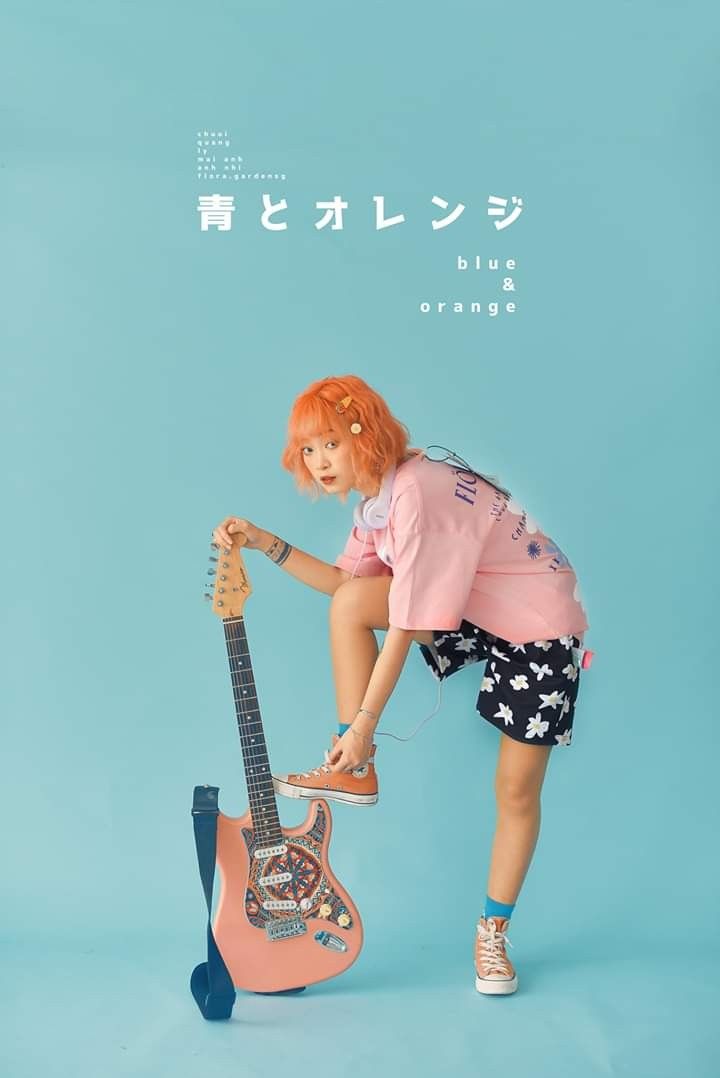 A girl with aorange hair holding a guitar.